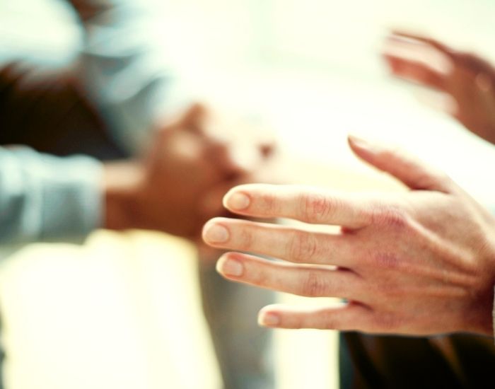 The hands of two people sitting close together while engaged in conversations.