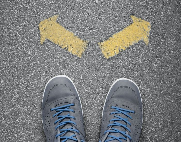 A pair of sneakered feet facing two choices in the form of yellow arrows representing the choice to stay the same or choose recovery.