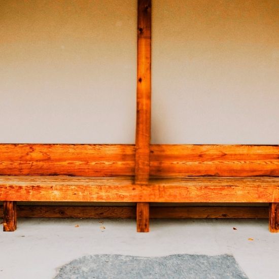 A dark haired woman sitting on a long wooden bench.