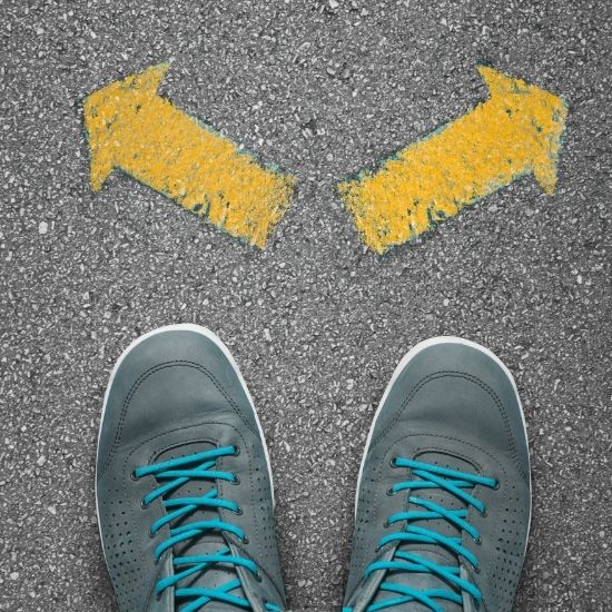 A pair of sneakered feet facing two choices in the form of yellow arrows representing the choice to stay the same or choose recovery.